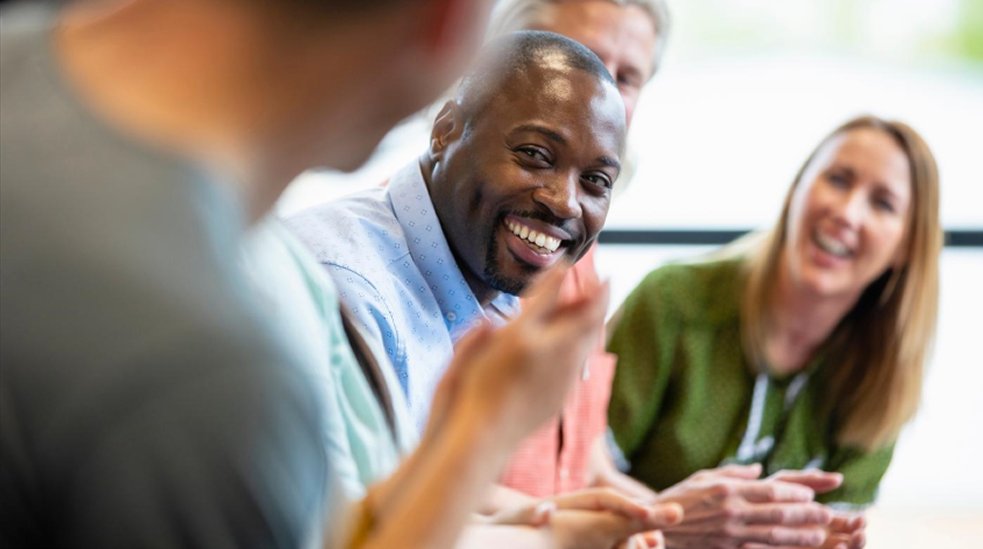 Smiling diverse team meeting around table collaborating in a bright modern office